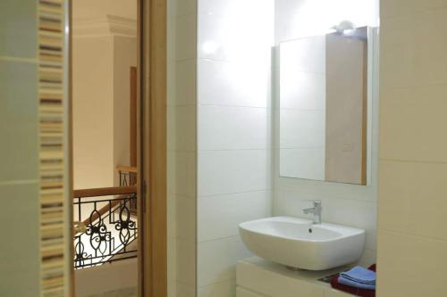 ein Badezimmer mit einem weißen Waschbecken und einem Spiegel in der Unterkunft Duplex face la résidence d ambassadeur de l Angleterre in La Marsa