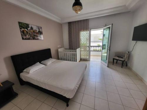 ein Schlafzimmer mit einem großen Bett und einem Balkon in der Unterkunft Duplex face la résidence d ambassadeur de l Angleterre in La Marsa