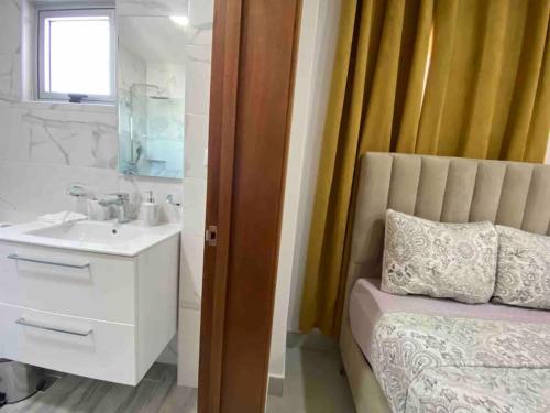 a bathroom with a bed and a sink and a mirror at Elegant City Center Condo in Santo Domingo