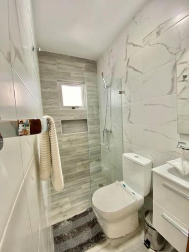 a white bathroom with a toilet and a shower at Elegant City Center Condo in Santo Domingo