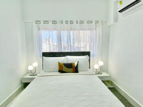 ein weißes Schlafzimmer mit einem großen Bett mit zwei Lampen in der Unterkunft Lovely City Center Condo in Los Prados