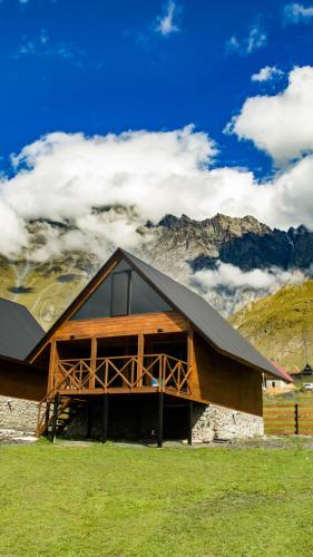 a large wooden building with mountains in the background at Cliffside cottage Kazbegi in Kazbegi