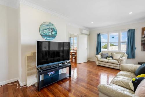 a living room with a large flat screen tv at The Brickstone Home with Deck and Parking in Auckland