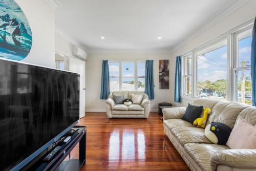 a living room with a couch and a large television at The Brickstone Home with Deck and Parking in Auckland