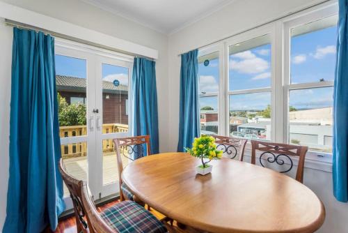 a dining room with a table and chairs and windows at The Brickstone Home with Deck and Parking in Auckland