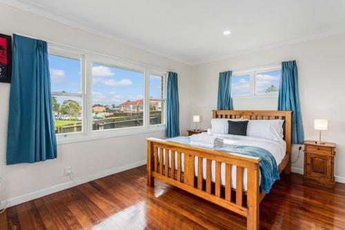 a bedroom with a bed and two windows with blue curtains at The Brickstone Home with Deck and Parking in Auckland