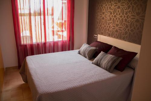 a bedroom with a bed with red curtains and a window at Acogedor adosado muy cerca de la playa in Almazora