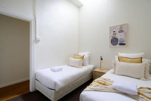Duas camas num quarto com paredes brancas em Eden-Stay like locals in Fitzroy North em Melbourne