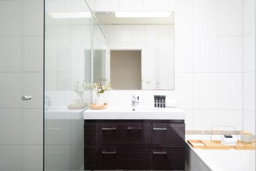 a white bathroom with a sink and a mirror at Eden-Stay like locals in Fitzroy North in Melbourne