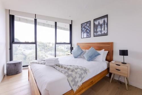 - une chambre avec un lit doté de draps blancs et d'oreillers bleus dans l'établissement Sanctuary-Effortless City Escape, à Melbourne
