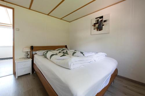 een slaapkamer met een bed met witte lakens bij 26, gelegen in het bosrijke Oisterwijk met privé tuin! in Oisterwijk