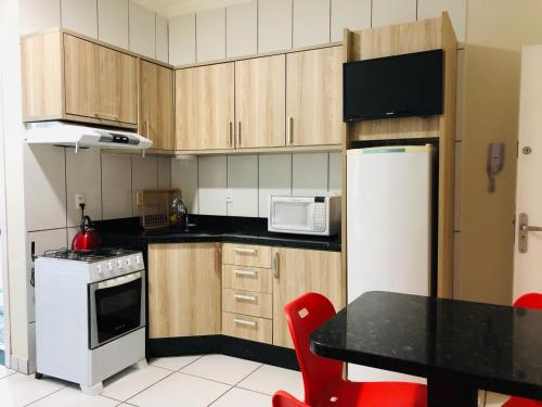uma cozinha com armários de madeira e um frigorífico branco em Chemin Suites em Balneário Camboriú