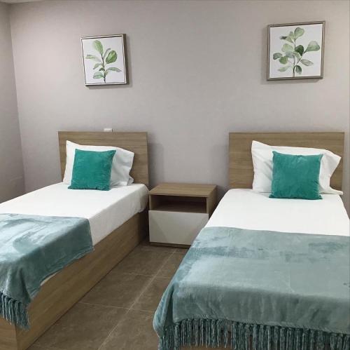 two beds in a hotel room with green pillows at Oceanview Apartments in Viana do Castelo