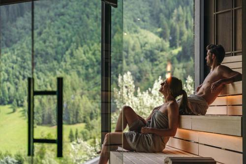 Duas mulheres sentadas no parapeito da janela, a olhar para as montanhas. em Arpuria l hidden luxury mountain home - ADULTS FRIENDLY em Sankt Anton am Arlberg