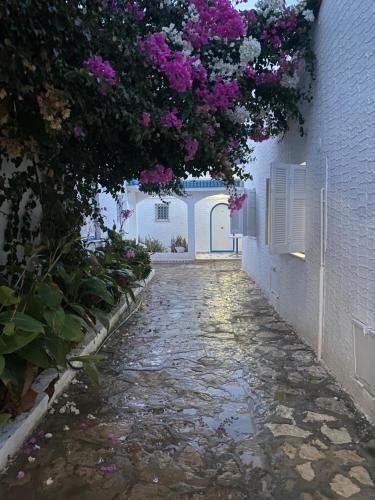 a stone walkway with purple flowers on a building at BUNGALOW El HOUDA in Hammamet