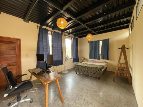 1 dormitorio con cama, escritorio y silla en Four Trees Jungle Lodge en San Juan del Sur
