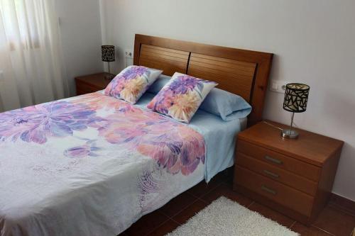 ein Schlafzimmer mit einem Bett mit Blumenbettdecke und einem Nachttisch in der Unterkunft CASA AREALBA Casa con piscina muy cerca de las playas de San Xurxo y Doniños in Ferrol