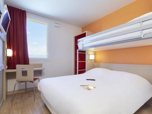 a bedroom with a large white bed and a desk at Premiere Classe Valence Nord - Saint Marcel Les Valence in Saint-Marcel-lès-Valence