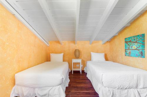 two beds in a room with orange walls at Villa Aloe in Paradijs