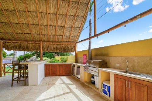 an outdoor kitchen with a bar and a table at Villa Aloe in Paradijs