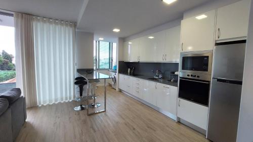 a kitchen with white cabinets and a table in it at Sol do Til Apartment in Funchal