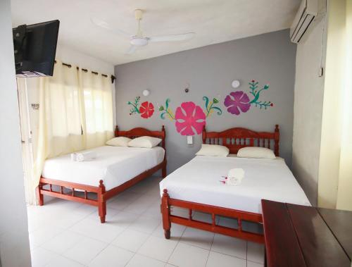 two beds in a room with flowers on the wall at Hotel Los Arcos Holbox in Holbox Island