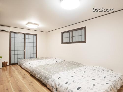 a white bedroom with a bed and two windows at WeeklyHouse Biwako Otsu - Vacation STAY 19732v in Otsu