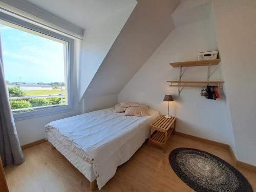 ein Schlafzimmer mit einem Bett und einem großen Fenster in der Unterkunft Maison traditionnelle et moderne avec vue mer in Tréffiagat