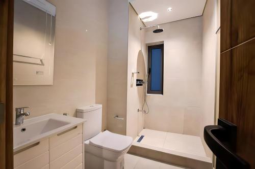 a white bathroom with a toilet and a sink at Exquisitely-detailed Home in Yaba, Lagos in Lagos