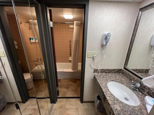 a bathroom with a sink and a shower and a phone at Hotel Lotus Kansas City Merriam in Merriam