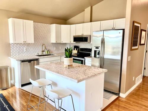a kitchen with a refrigerator and a counter with stools at Contemporary Turnagain Townhome in Anchorage