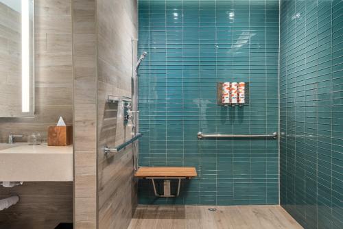 a bathroom with green tiles and a shower with a bench at EAST Miami in Miami