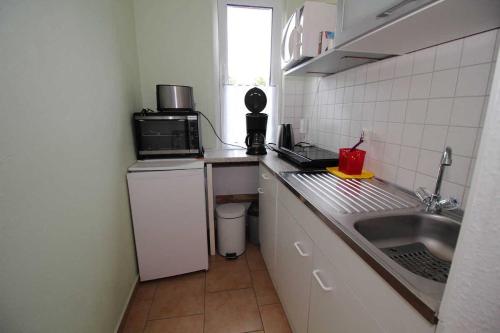uma pequena cozinha com um lavatório e um micro-ondas em Ferienhaus Frisch em Sassnitz