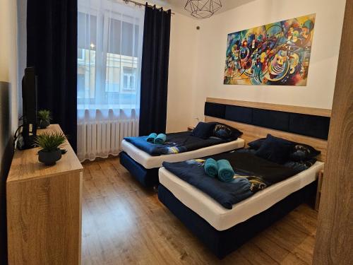 Habitación con 2 camas en una habitación con una pintura en Apartamenty KoktajLOVE, en Kielce