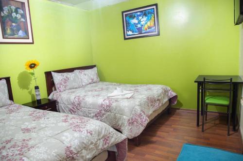 Grünes Zimmer mit 2 Betten, einem Tisch und einem Schreibtisch in der Unterkunft Downtown in Quito