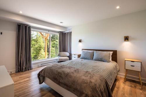 a bedroom with a bed and a large window at Chalet Alpine by Tremblant Platinum in La Conception
