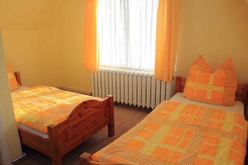 een slaapkamer met 2 bedden en een raam met oranje gordijnen bij Ferienwohnung Karger in Marlow