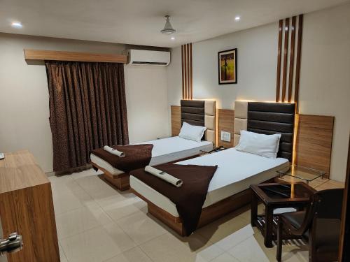 a hotel room with two beds and a desk at HOTEL SAHYOG & ROOMS in Surat