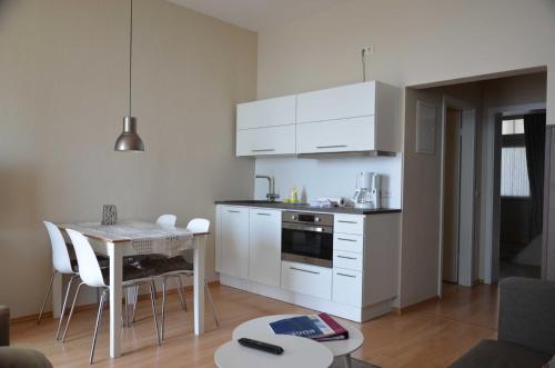a kitchen with white cabinets and a table with chairs at Fürstenhof - Ferienwohnung 203 in Sassnitz