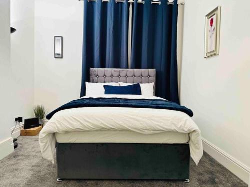 a bedroom with a large bed with blue curtains at Bespoke 2 Bedroom Apt Derby City in Derby