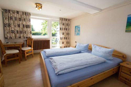 Schlafzimmer mit einem Bett mit blauer Bettwäsche und einem Fenster in der Unterkunft Ferienzimmer zum Försterberg in Hagen