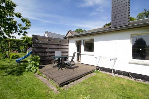 a wooden deck with a table and chairs in a yard at Ferienzimmer zum Försterberg in Hagen