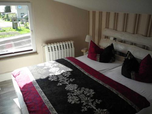 Schlafzimmer mit einem Bett mit roten Kissen und einem Fenster in der Unterkunft Ferienwohnung BoddenBlick in Polchow