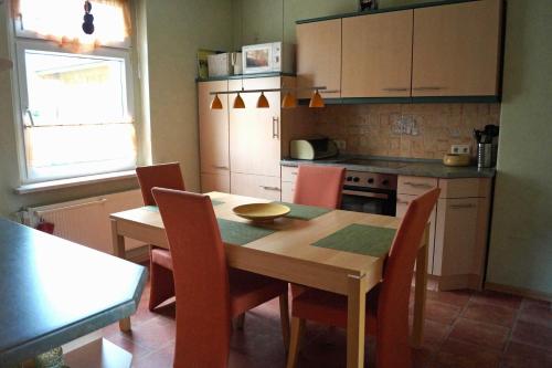 eine Küche mit einem Holztisch und Stühlen sowie eine Küche mit einem Herd in der Unterkunft Ferienwohnung Frömming in Sassnitz