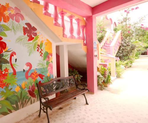 a bench sitting in front of a wall with a mural at Hotel Los Arcos Holbox in Holbox Island