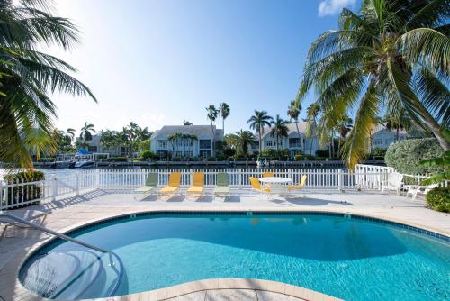 a swimming pool with palm trees and houses at Snug Harbour View Condo #5 in George Town