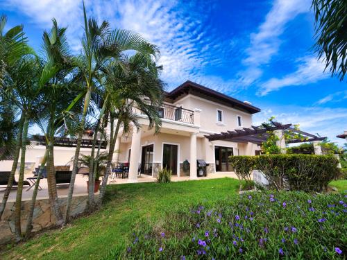 a house with palm trees and a lawn with purple flowers at Luxury Villa In Prestigious Pristine Bay, Home Of The Black Pearl Golf Course in French Harbour