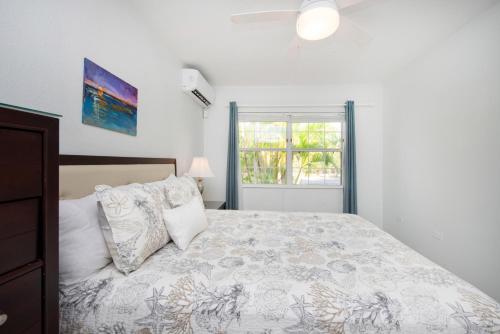 - une chambre blanche avec un lit et une fenêtre dans l'établissement Snug Harbour View Condo #1, à George Town