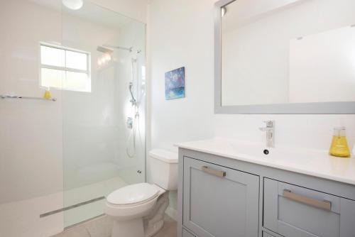 La salle de bains blanche est pourvue d'une douche et de toilettes. dans l'établissement Snug Harbour View Condo #1, à George Town