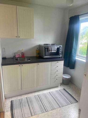 a kitchen with a microwave on top of a counter at Liten eldre og koselig studiohybel in Svolvær